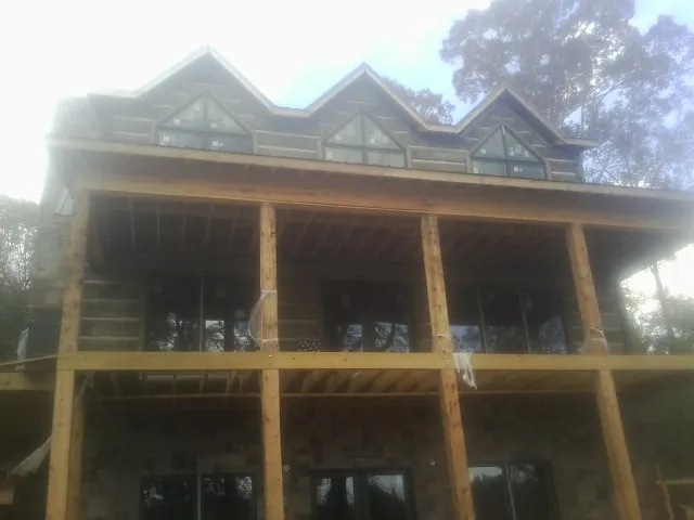 Dormers and porch framing on a large log home under construction — Roof Coating work by our crew in Sedalia